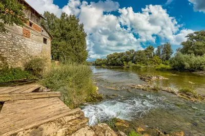 a river next to a brick building and a bridge at River View Suite Mlinar Private Beach - Happy Rentals in Metlika