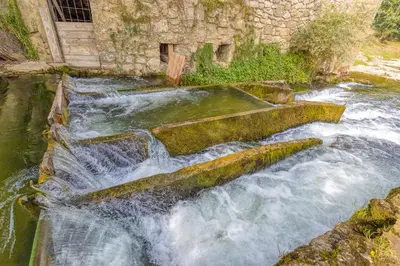 a waterfall in a river with rocks in the water at River View Suite Mlinar Private Beach - Happy Rentals in Metlika