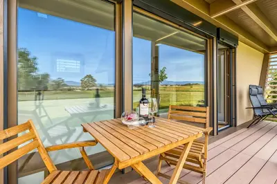 a wooden table on a porch with a bottle of wine at Riverside Suite Mobile Homes in Gradac