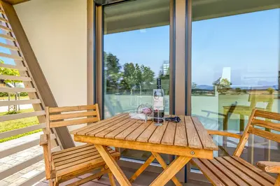 a wooden table sitting on a porch with two chairs at Riverside Suite Mobile Homes in Gradac