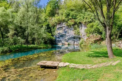 a wooden bench sitting in the middle of a river at Riverside Suite Mobile Homes in Gradac
