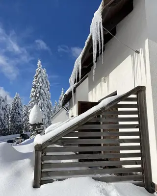 a snow covered building with icicles hanging from it at Apartma Idila in Zreče