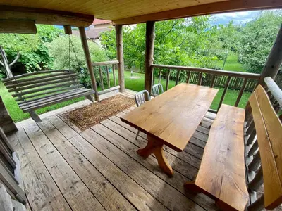 a wooden table and bench on a porch with a swing at Chalet Sejalec in Lesce