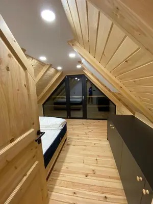a small bedroom with a bed and a wooden floor at Brunarica Chalet Rogla Sauna in Vitanje