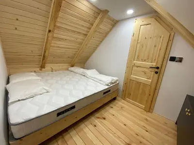 a small bed in a room with a wooden floor at Brunarica Chalet Rogla Sauna in Vitanje