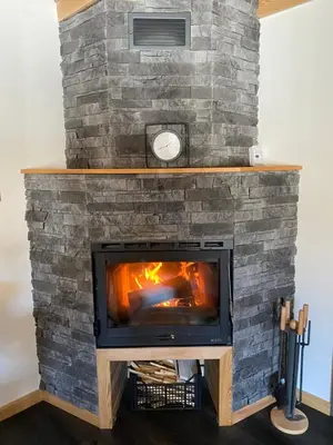a stone fireplace with a fire in it at Brunarica Chalet Rogla Sauna in Vitanje