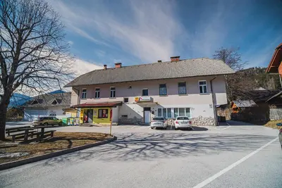 a large white building with two cars parked in front of it at Studio CENTER in Zgornje Jezersko