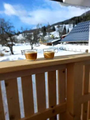 two cups of coffee on a wooden railing with snow at Deluxe Apartments 55 in Kranjska Gora