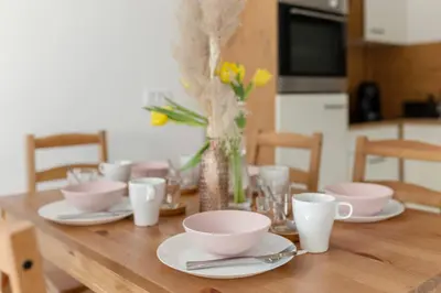 a wooden table with plates and cups and flowers on it at Deluxe Apartments 55 in Kranjska Gora