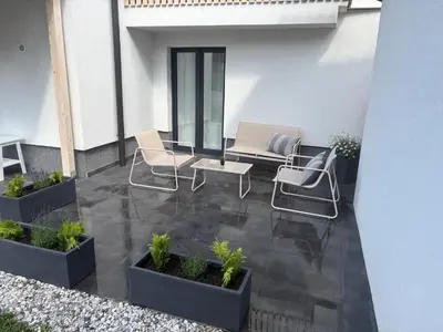 a patio with two chairs and a table and some plants at Deluxe Apartments 55 in Kranjska Gora