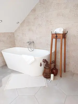 a white bath tub in a bathroom with a tile wall at BEe in foREST in Pivka