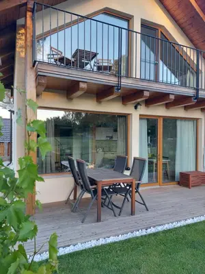 a deck with a wooden table and chairs on a house at BEe in foREST in Pivka