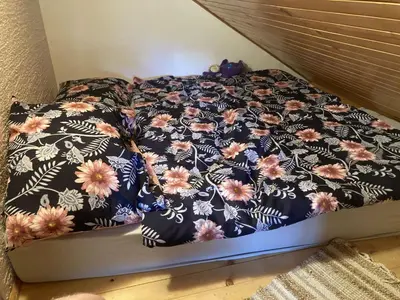 a bed with a black and white bedspread with flowers at Vineyard Cottage Slanc in Metlika