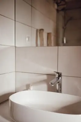 a white sink in a bathroom with white tiles at Ecological farm Makrobios Panonija in Gornji Petrovci