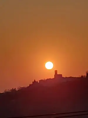 a sunset over a city with the sun in the sky at Apartmaji Aucin - Brda in Kojsko