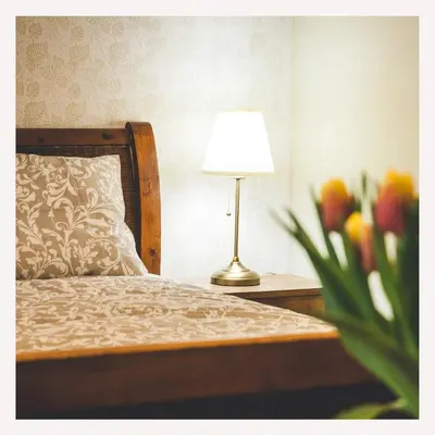a bedroom with a bed with a lamp and a vase of flowers at Apartmaji Aucin - Brda in Kojsko