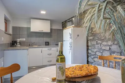 a bottle of wine sitting on a table with a pizza at Vineyard cottage Kolpa Zupančič in Stari Trg ob Kolpi