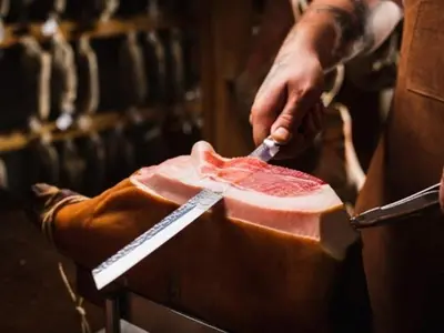 a person cutting a piece of meat with a knife at Apartma Uhanje pri Božičevih in Ajdovščina