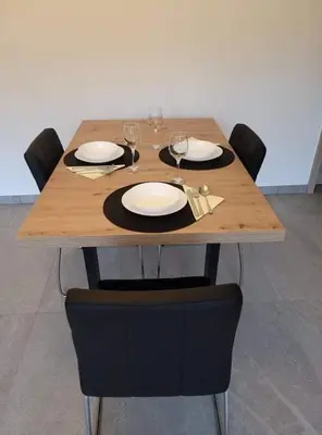 a wooden table with chairs and plates and wine glasses at Apartma Uhanje pri Božičevih in Ajdovščina