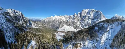 a mountain range with snow covered mountains and trees at Erjavčeva mountain hut at Vršič pass in Kranjska Gora