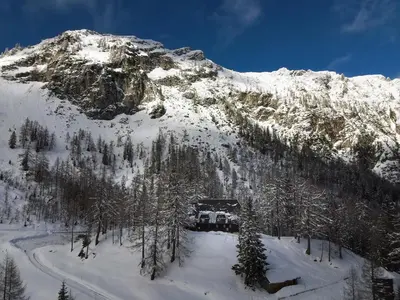 a mountain covered in snow with a house on it at Erjavčeva mountain hut at Vršič pass in Kranjska Gora