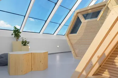 a room with a large window and wooden stairs at Honeybee Hostel - Hiša kranjske čebele in Višnja Gora