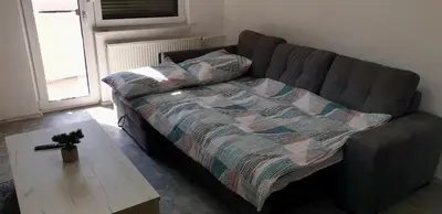 a couch with a blanket and a coffee table in a living room at Apartma Sivi žako in Bohinj