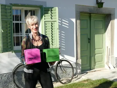 a woman standing in front of a house with a bike at House 1797 - Charm of Slovenian Vintage in Dob