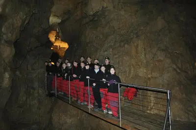a group of people standing on a railing in a cave at House 1797 - Charm of Slovenian Vintage in Dob