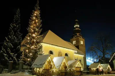 a church with a christmas tree in front of it at Apartma Studio Jana in Kranjska Gora