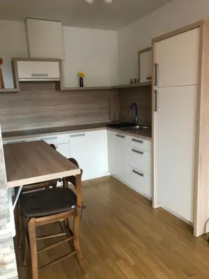 a kitchen with white cabinets and a table and a refrigerator at Apartma Ajda 2 , Jezerska cesta 65, Kranj in Kranj