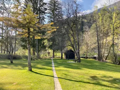 a path in a park with a bridge and trees at Studio Mila in Kranjska Gora
