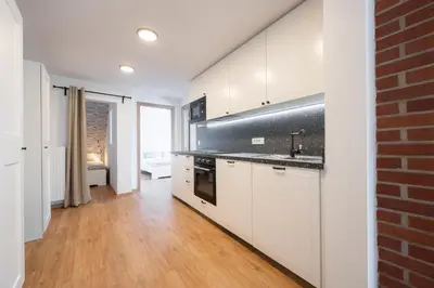 a kitchen with white cabinets and a brick wall at GrosAlp apartments in Lesce