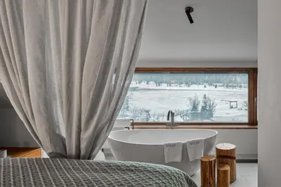 a bath tub in a bedroom with a window at Milka Boutique Hotel in Kranjska Gora
