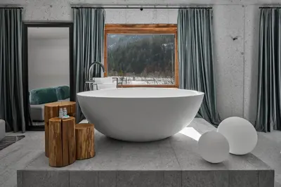 a large white bath tub in a bathroom with a window at Milka Boutique Hotel in Kranjska Gora