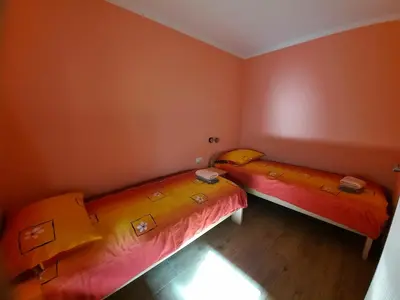 two beds in a room with orange walls at Apartment Pretner, Lepena in Soča