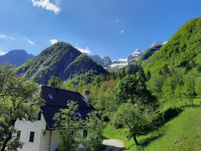 a house in a valley with mountains in the background at Apartment Pretner, Lepena in Soča