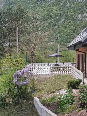 a garden with an umbrella next to a house at Apartma V&T in Bovec