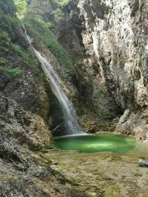 a waterfall in a canyon with a green pond at Apartma V&T in Bovec