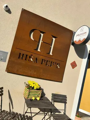 a sign on a wall with a table and flowers at Hiša Pep's in Ivanjkovci