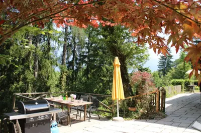 a patio with an umbrella and a table and a grill at Panoramic Forest Chalet Bled Lake and Castle View in Bled