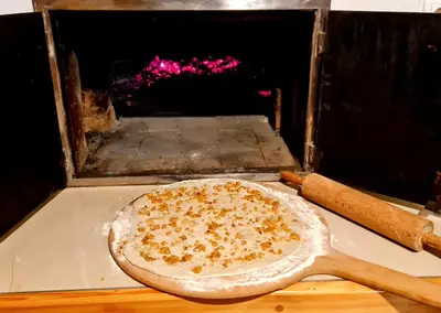 a pizza in an oven with a wooden spatula at Turistična kmetija Hiša ob gozdu pri Ptuju in Ptuj