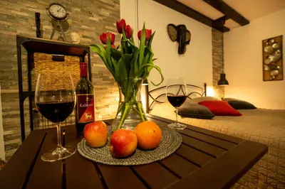 a table with a vase of red tulips and fruit and wine glasses at Pleasant Apartments in Bled