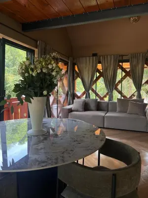 a living room with a glass table and a vase with flowers at Ranč Mackadam Ranch Mackadam in Tržič