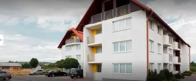 a white building with cars parked in a parking lot at Apartma Moravske Toplice 16 in Moravske Toplice