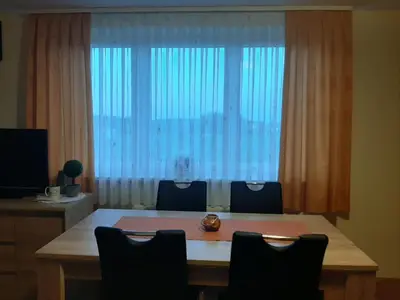 a dining room table with chairs and a large window at Apartma Moravske Toplice 16 in Moravske Toplice