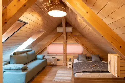 a room with a couch and a bed in a attic at Glamping Happiness - Natural Pool & Wellness in Ribnica