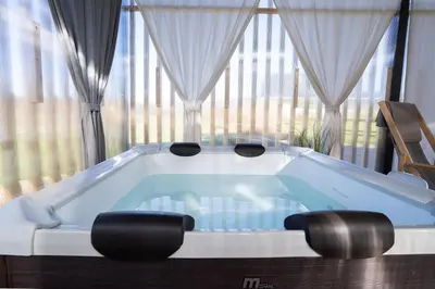 a bath tub with two stools in front of a large window at Glamping Happiness - Natural Pool & Wellness in Ribnica