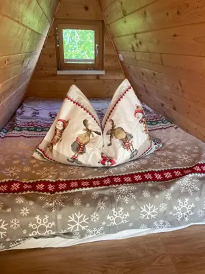 a bed in a tree house with pillows at NEW! Glamping House with new hot tub and sauna- Hisa oddiha UPDATED DECEMBER 2025 in Smarjeske Toplice