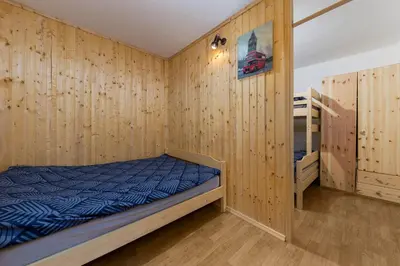 a bedroom with a bed and wooden walls at Apartma Valsar Rogla in Zreče